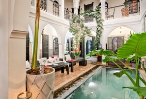 A luxurious indoor pool area with a seating area, potted plants, and a clear view of the pool. - Riad Al Boraq (Marrakech)