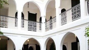 Um pátio com área de estar central, arcos brancos e grades decorativas.
