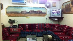 Una sala de estar con un amplio sofá modular, una mesa de centro, un televisor y un cuadro en la pared.