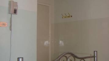 Una habitación con estructura de cama de metal, televisión montada en la pared y teléfono.