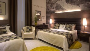 Een hotelkamer met twee bedden, een bureau, een stoel, een groot muurdecor en een potplant.