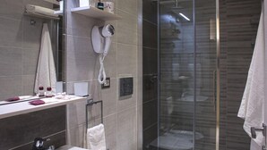 Een moderne badkamer met een douchecabine van glas, een wastafel met twee kommen en een toilet.
