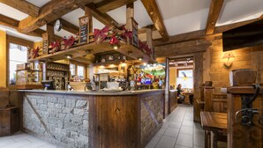 Un rústico bar con barra de piedra, vigas de madera y un ambiente acogedor.