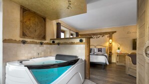 Un baño moderno con una bañera grande, techo de madera y una cama con edredón de cuadros.