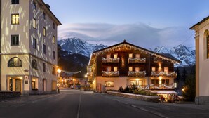 Un hotel con varios balcones, fachada de piedra y vistas a montañas nevadas.