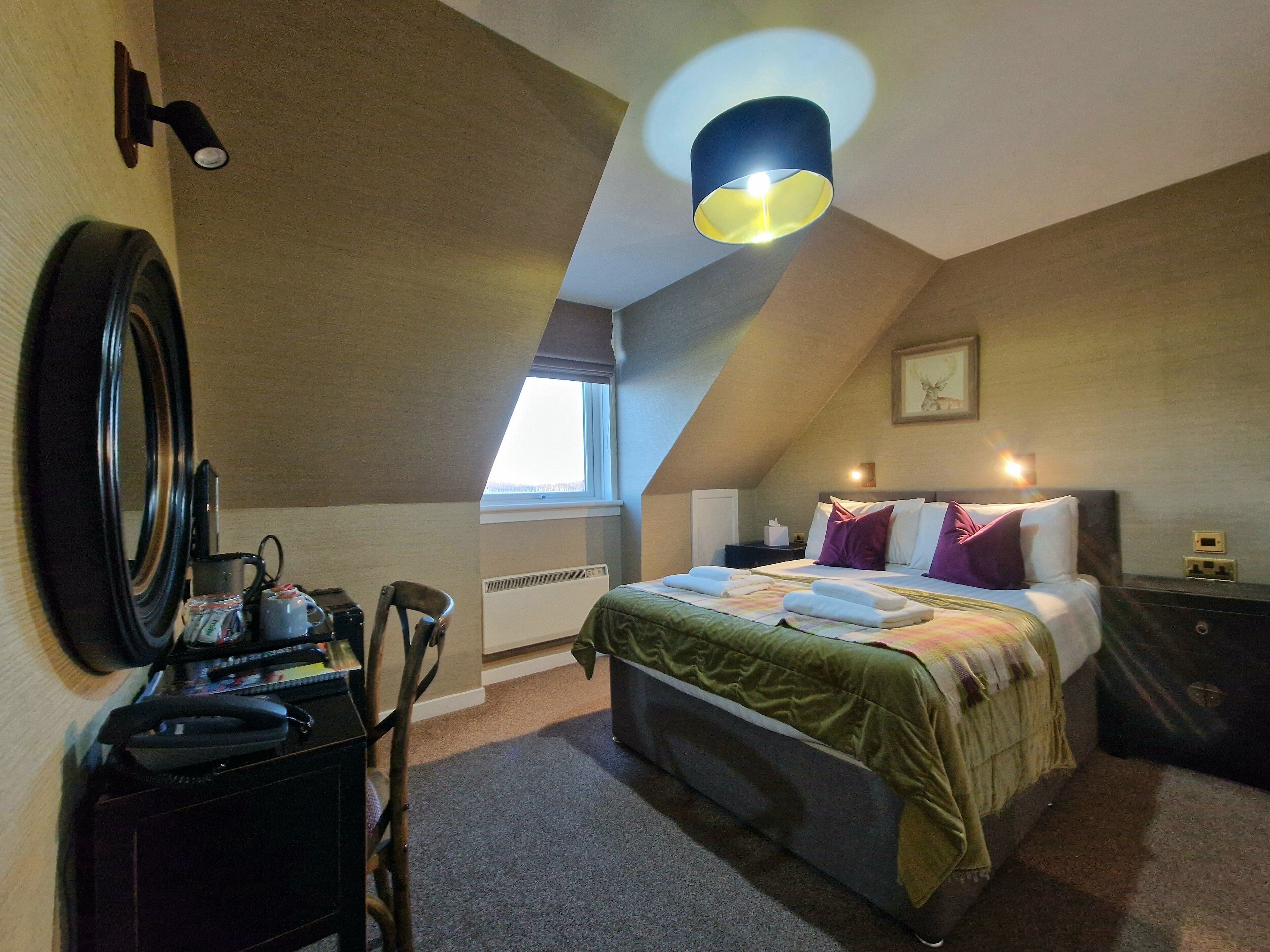Une chambre à coucher avec un lit, une table de chevet, une lampe et une fenêtre.