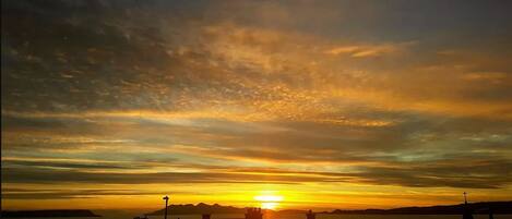 Un atardecer sobre una masa de agua con edificios silueteados al frente.