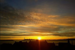 Un atardecer sobre una masa de agua con edificios silueteados al frente.