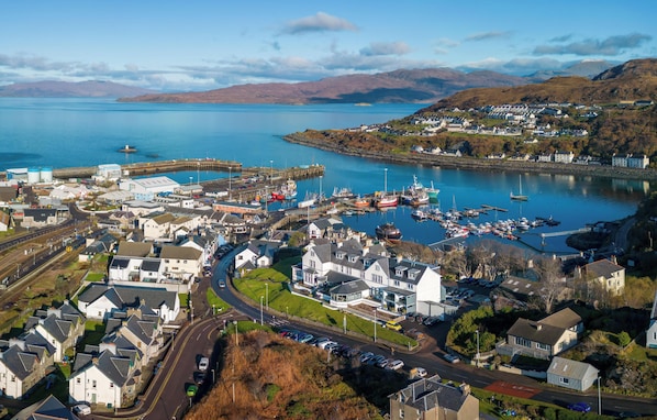 Vista aérea del Hotel West Highland, con un puerto deportivo con barcos, una vía ferroviaria y edificios residenciales.