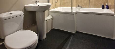 Een moderne badkamer met toilet, wastafel en bad.