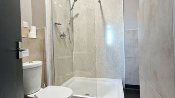 Une salle de bain moderne équipée de toilettes, d’une douche à parois de verre et d’une baignoire.