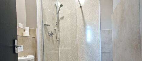 A modern bathroom with a toilet, a glass-enclosed shower, and a bathtub.