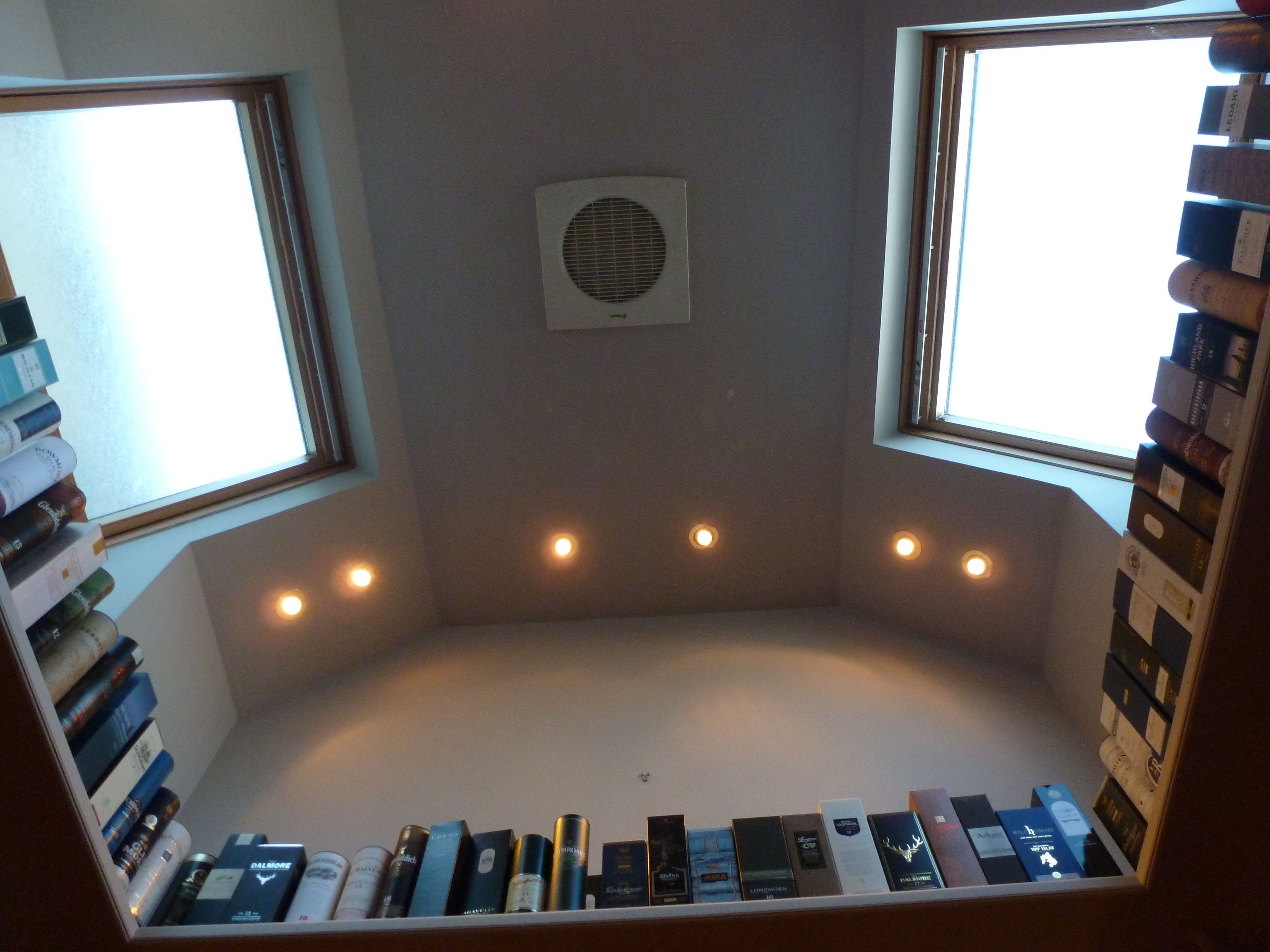 Une pièce dotée d’un coin salon intégré, d’un ventilateur de plafond et d’étagères murales.