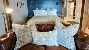 A bedroom with a large bed, a brown leather sofa, and a blue headboard. - West Highland Hotel (Mallaig)