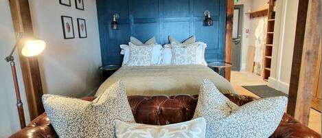A bedroom with a large bed, a brown leather sofa, and a blue headboard.