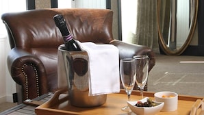 A leather armchair with a bottle of champagne and two glasses on a tray, a bowl of olives, and a small bowl of nuts. - West Highland Hotel (Mallaig)