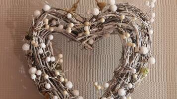 A heart-shaped wreath with white and green berries hanging on a textured wall.