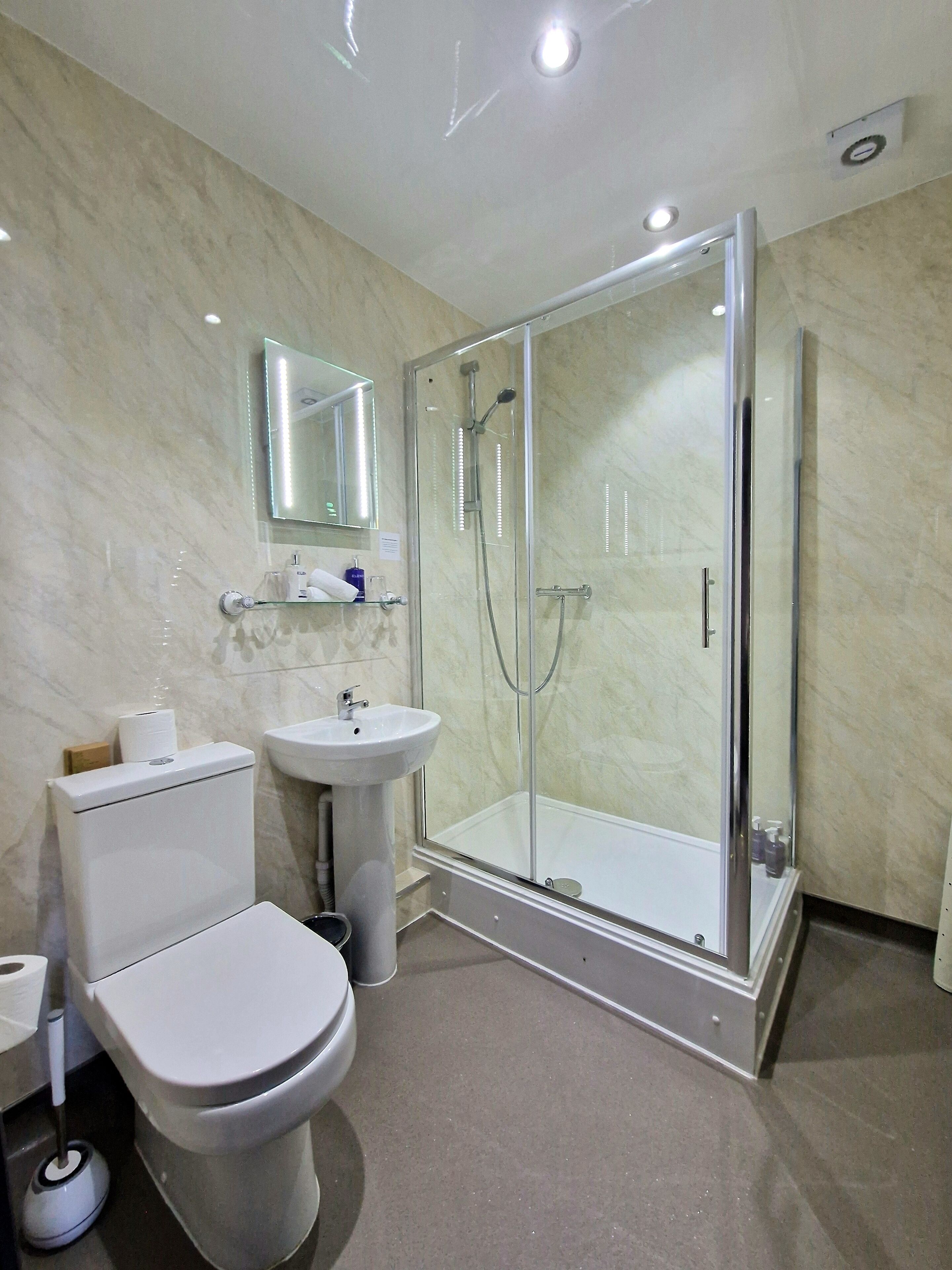 A modern bathroom with a toilet, sink, and glass-enclosed shower.
