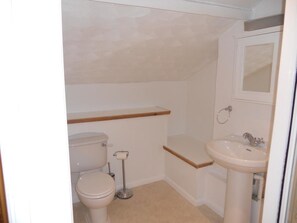A small, clean bathroom with a toilet, sink, and a mirror above the sink.