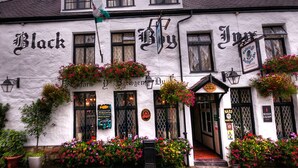 A traditional pub with a white facade, black lettering, and flower boxes. - Black Boy Inn (Caernarfon)