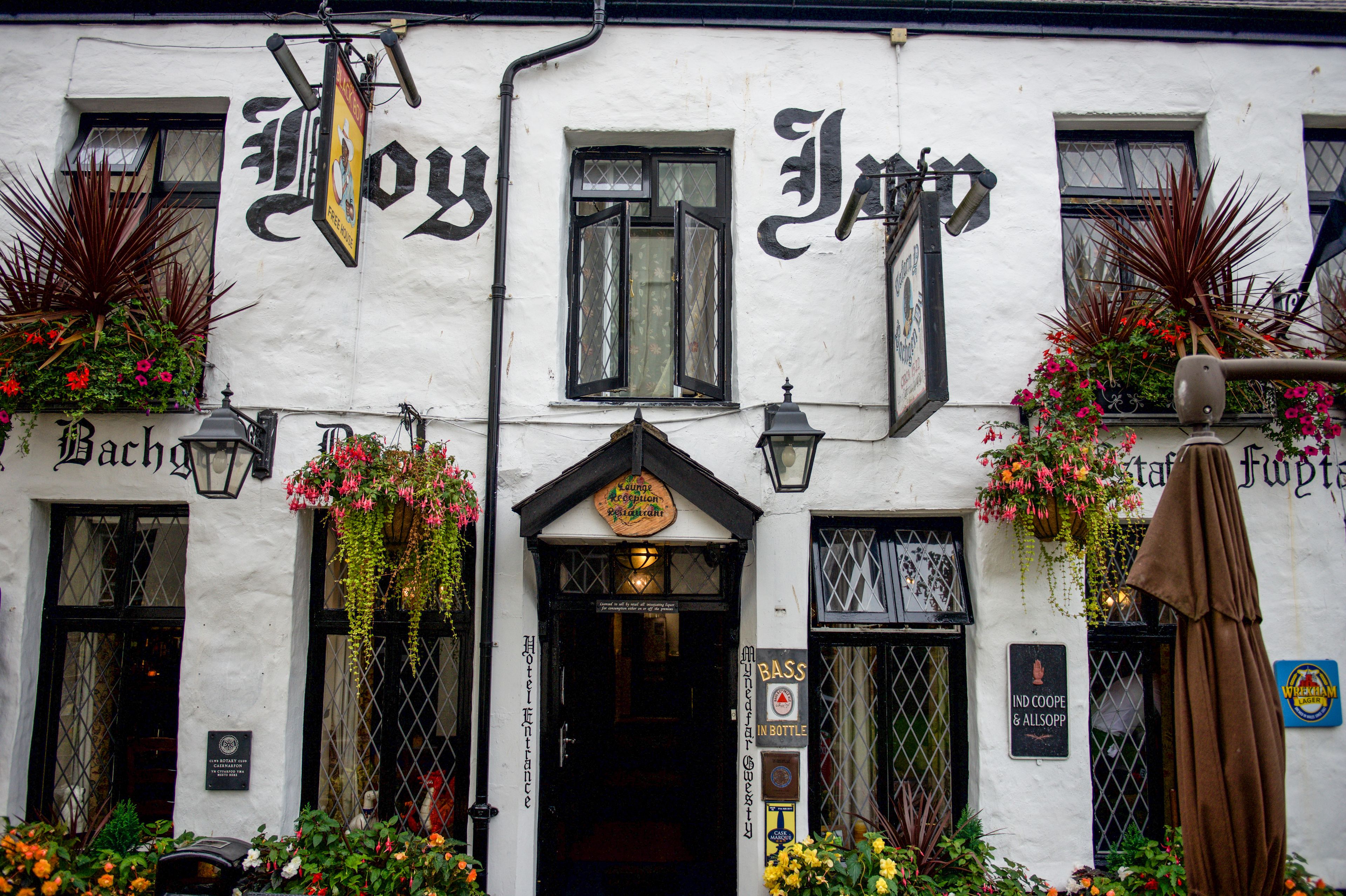 A building with a white facade, black-framed windows, and hanging flower baskets.