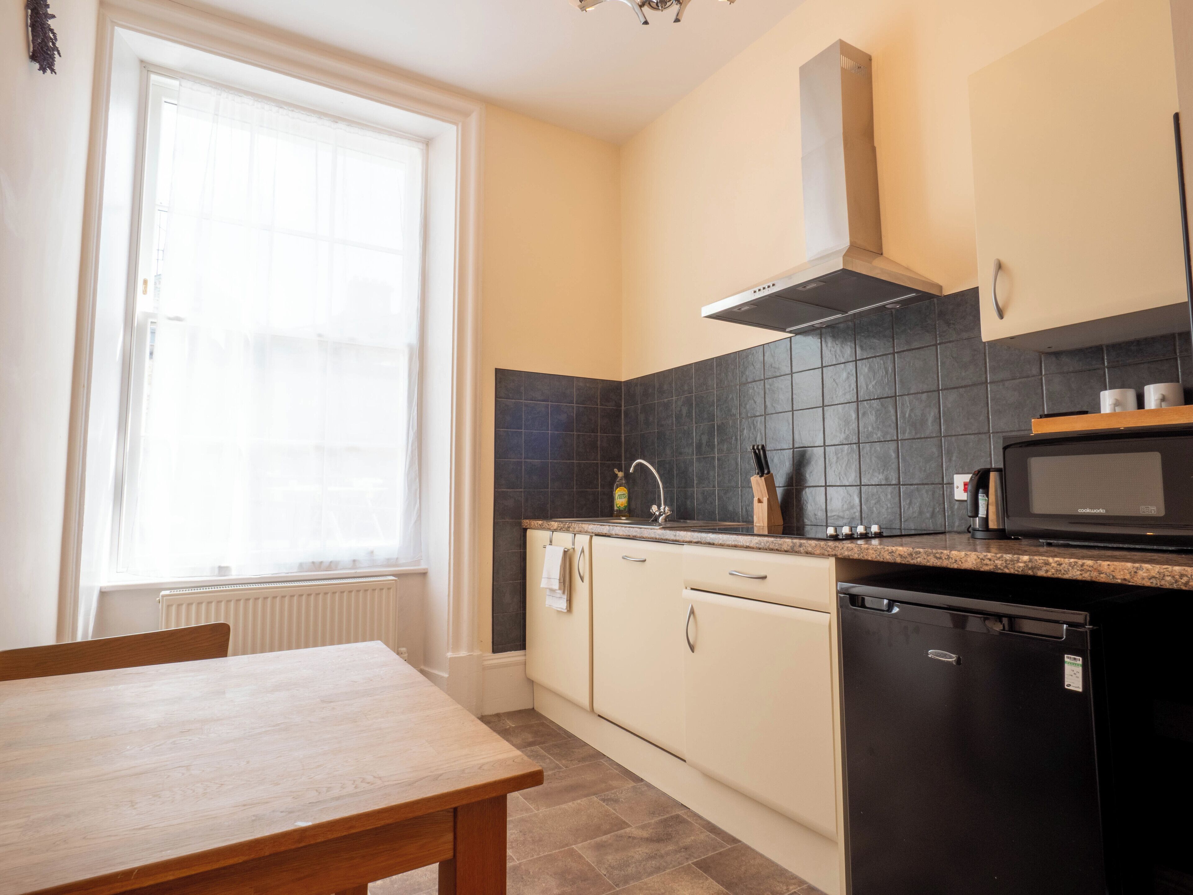 A compact kitchen with a window, a built-in stove, a microwave, and a dishwasher.