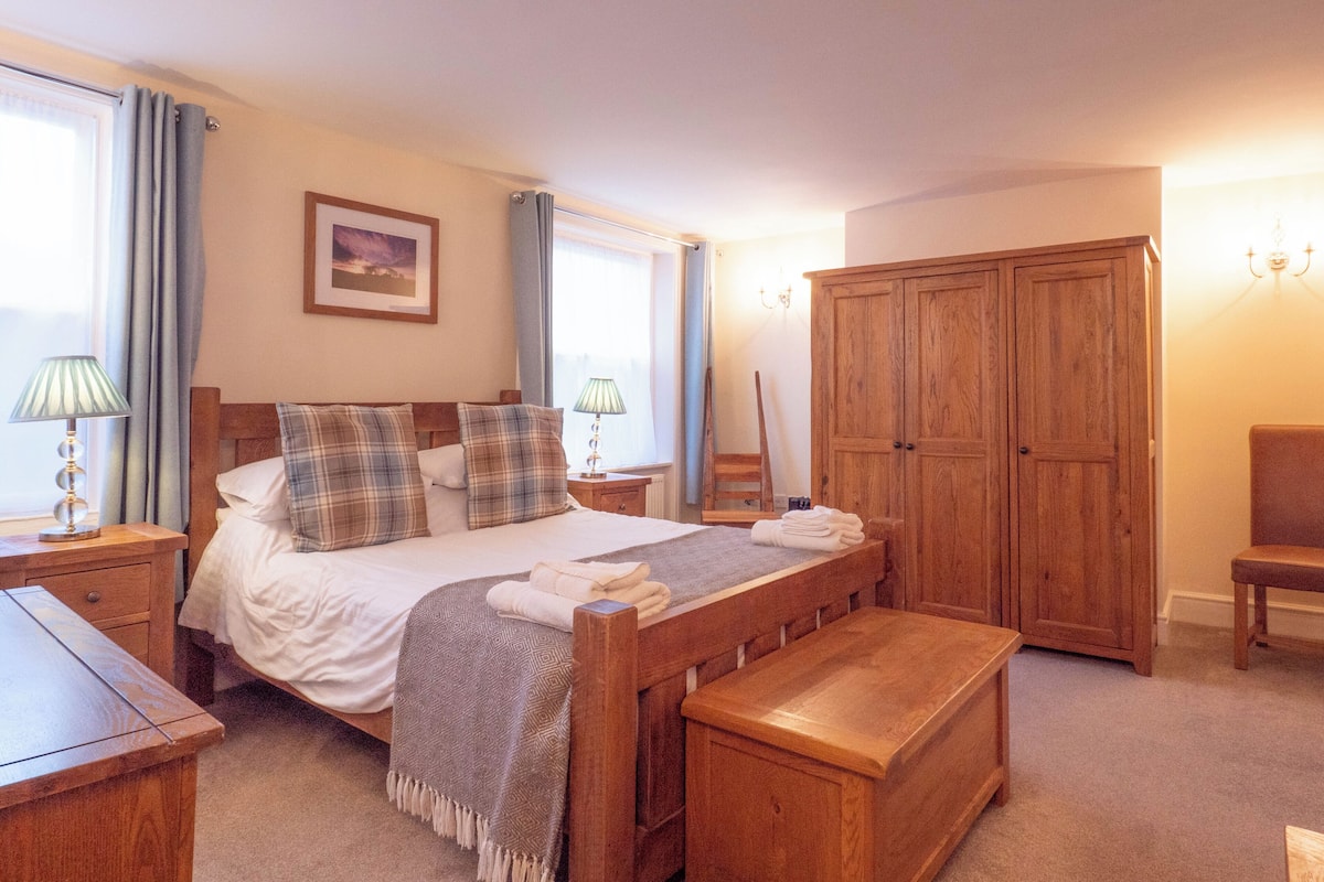 Ein Schlafzimmer mit einem hölzernen Bett, einer Holzbank, einem Holzschrank und einem Holztisch.