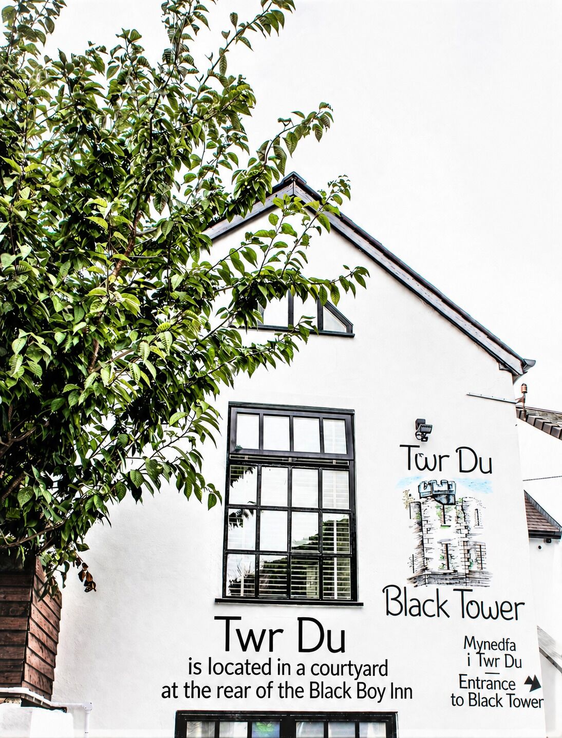Een gebouw met een bord waarop 'Twr Du Black Tower' staat, gelegen in een binnentuin.