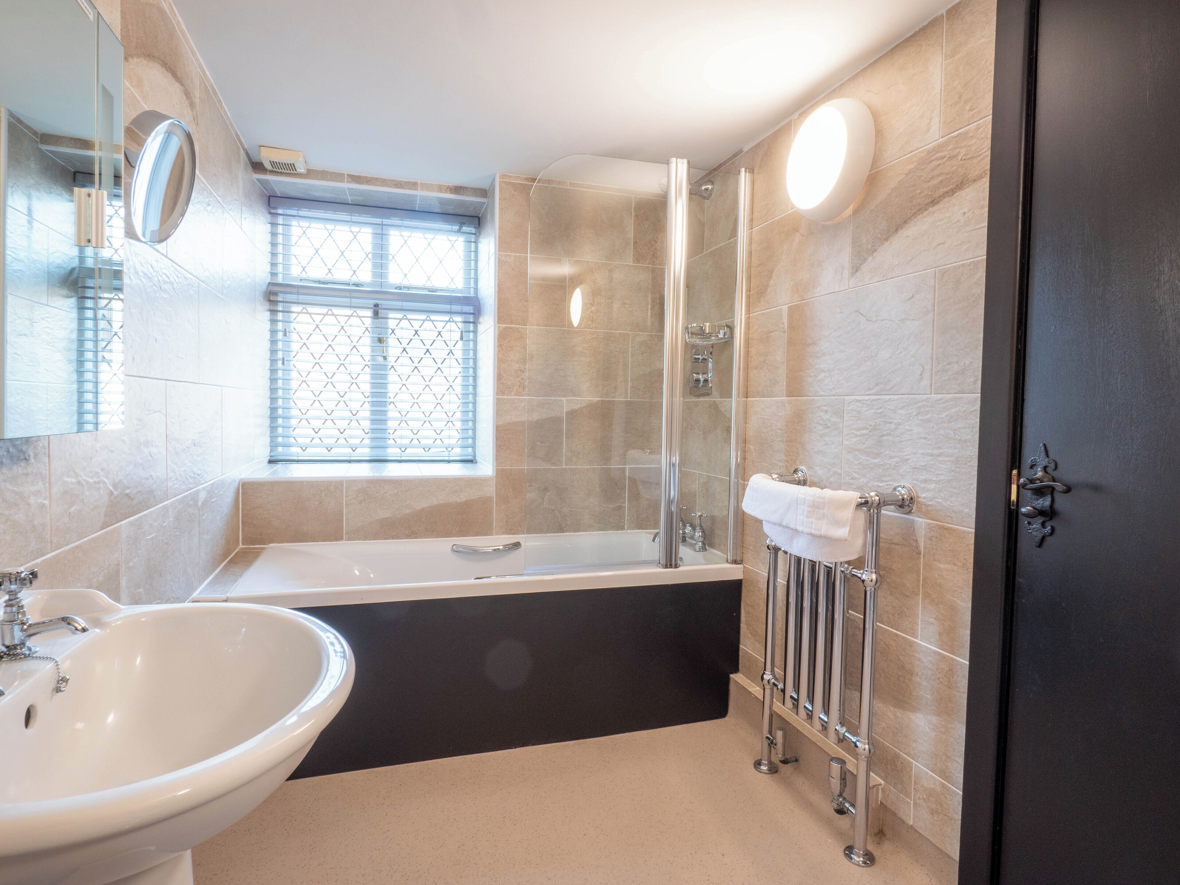 Un baño moderno con bañera, lavabo y mampara de vidrio.