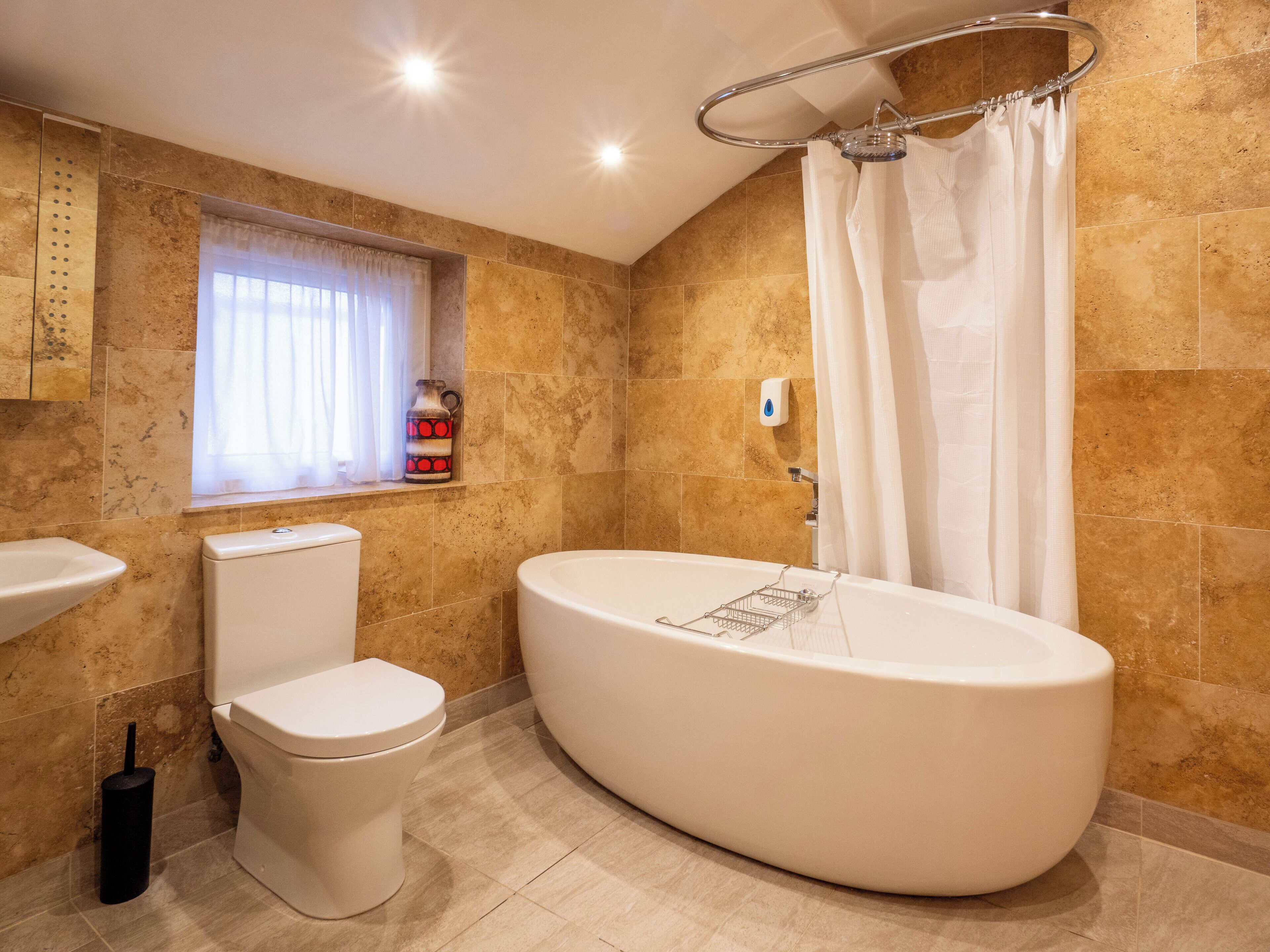 A modern bathroom with a freestanding bathtub, a toilet, and a sink.