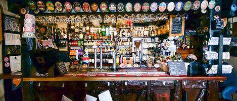 A bar with a variety of bottles and a selection of beer taps.