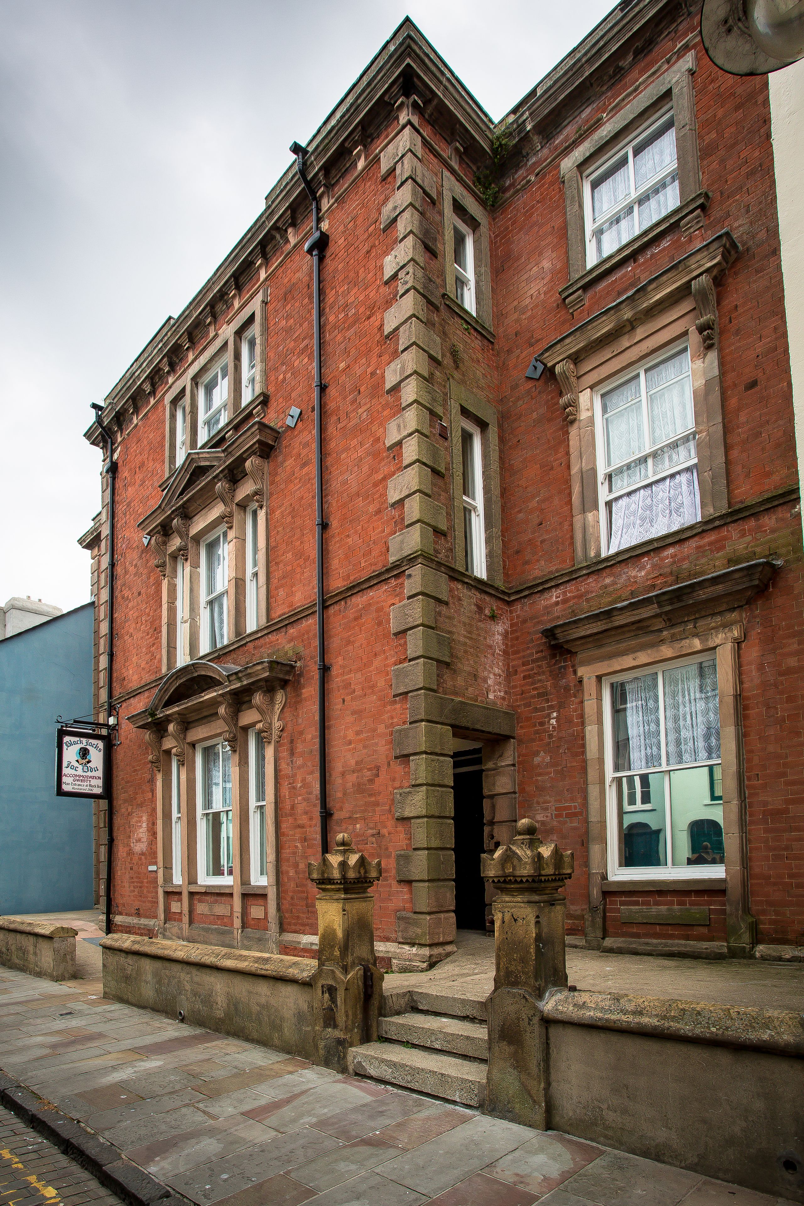 A red brick building with multiple windows and a signboard.