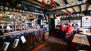 A bar with a wooden counter, shelves of bottles, and a rustic interior. - Black Boy Inn (Caernarfon)