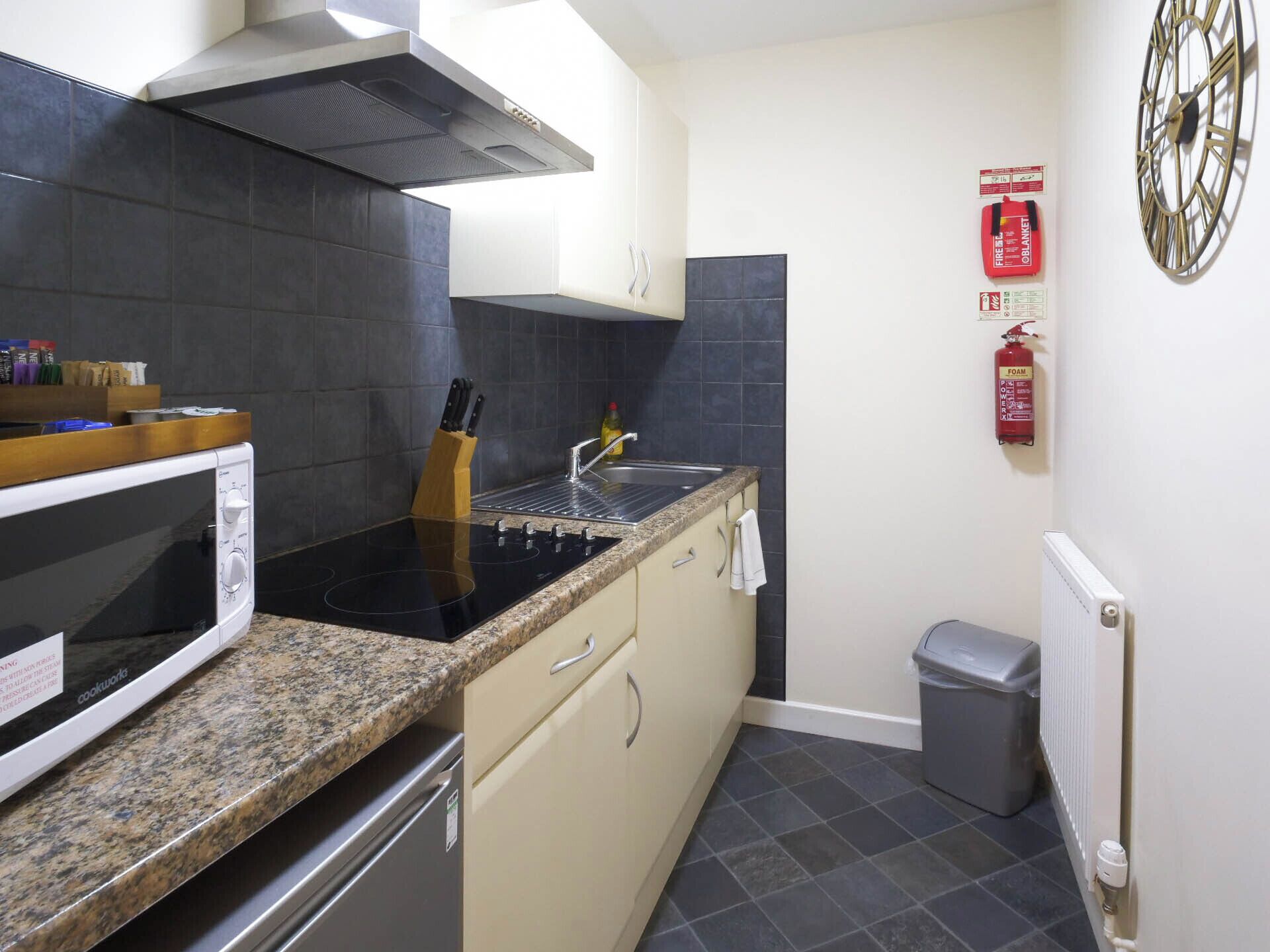 A compact kitchen with a stove, microwave, and sink.