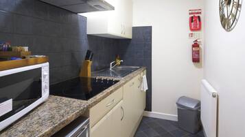 A compact kitchen with a stove, microwave, and sink.
