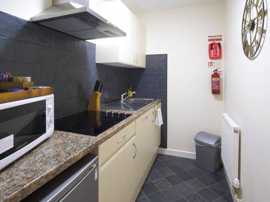 A compact kitchen with a stove, microwave, and sink.