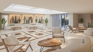 A spacious living area with a high ceiling, a large window, and a cactus wall art. There are multiple seating options including sofas and chairs. - Iberostar Waves Creta Panorama & Mare (Mylopotamos)