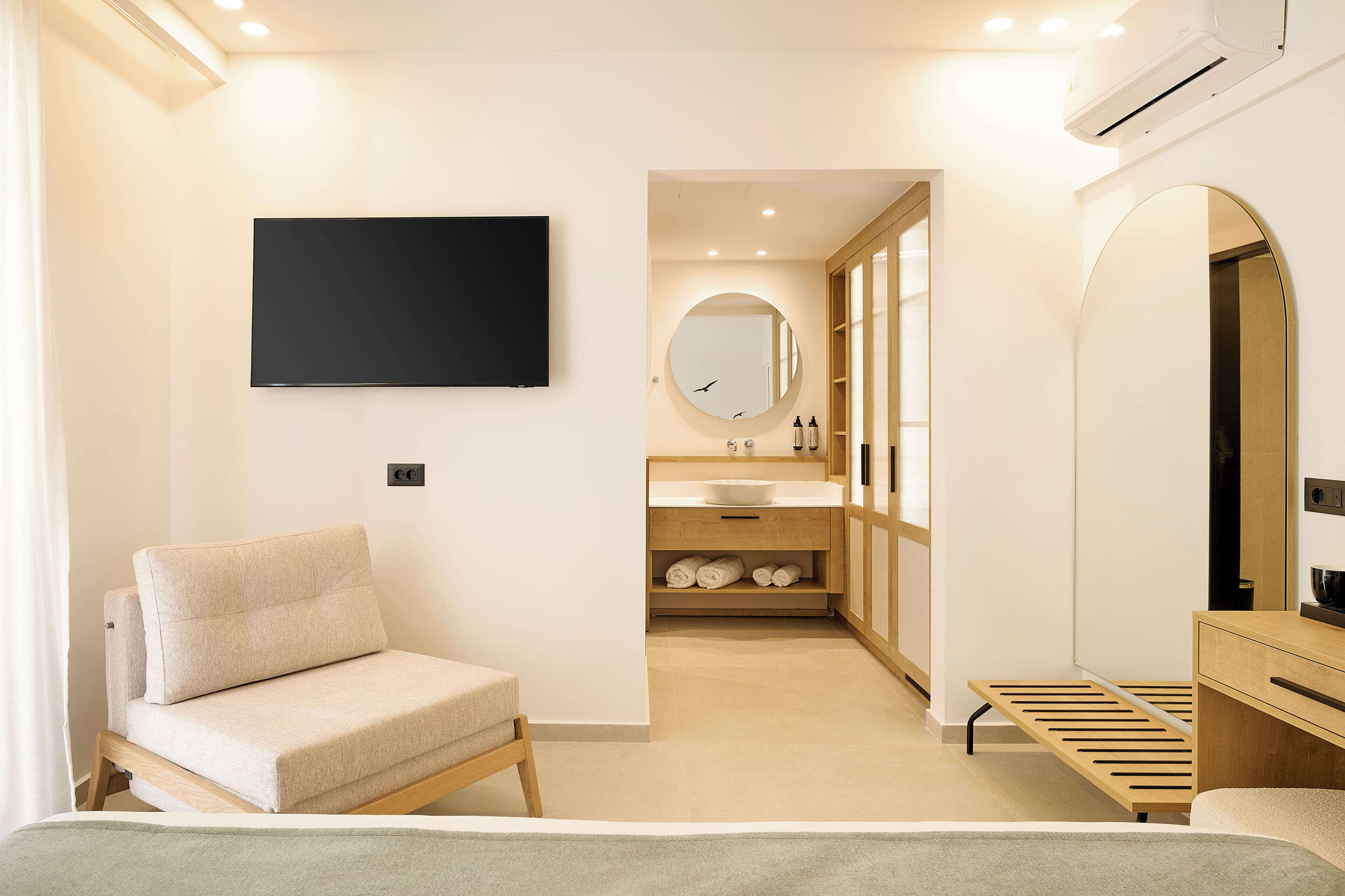 Un dormitorio moderno con sofá, televisor, mesita de noche y vestidor.