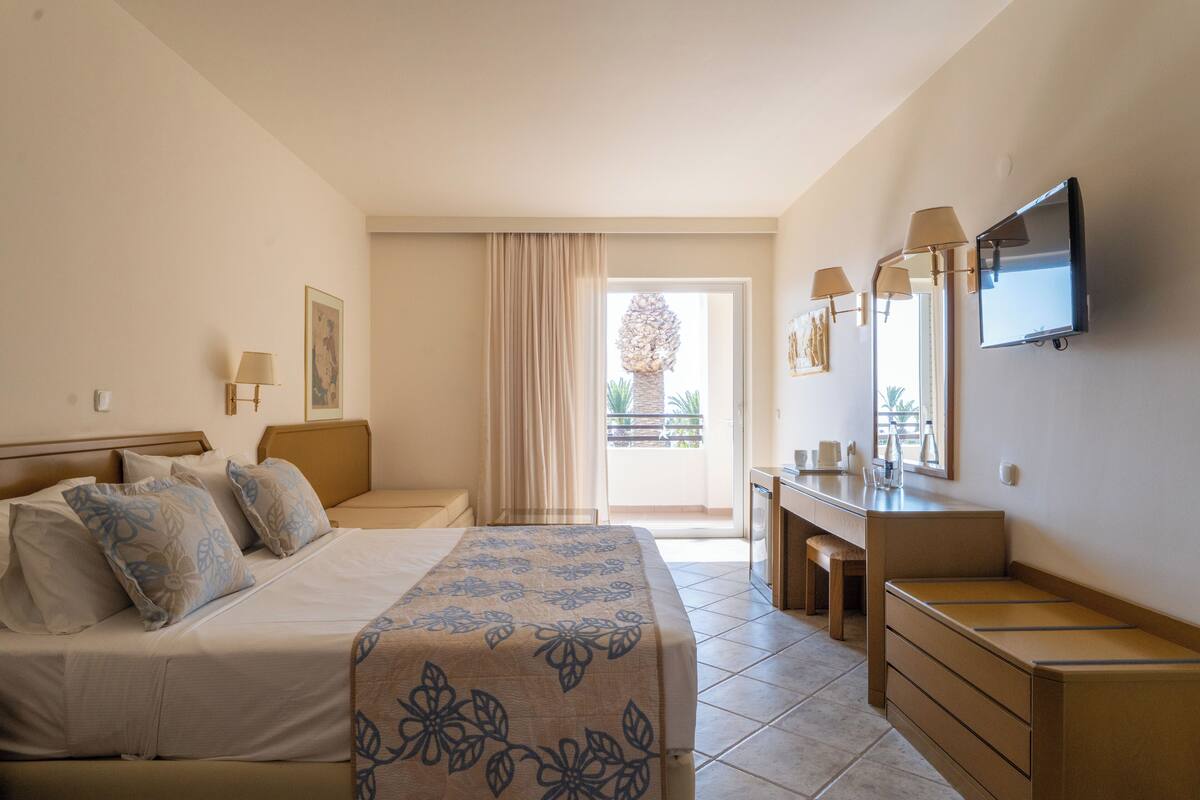 Une chambre d’hôtel comprenant un lit, une table de chevet, une commode et un téléviseur fixé au mur.