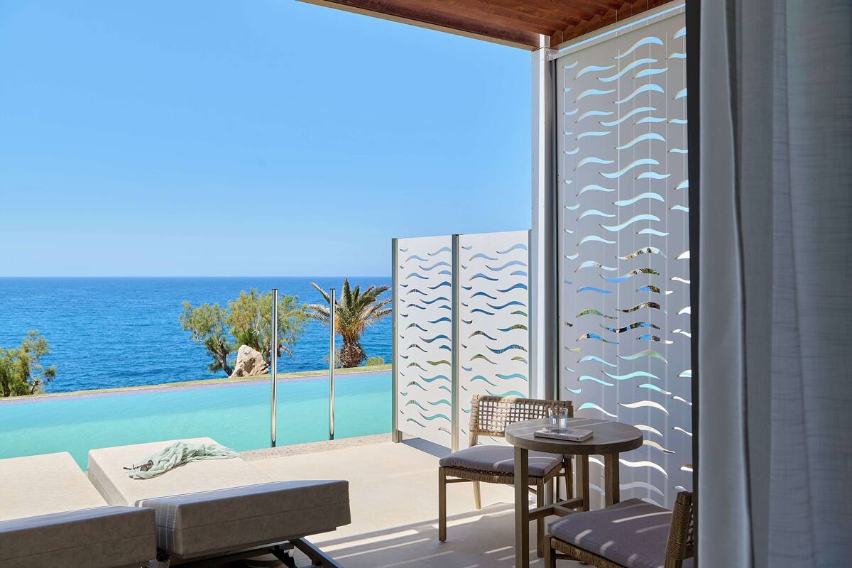 Un balcon avec vue sur la mer, une piscine et une table avec des chaises.