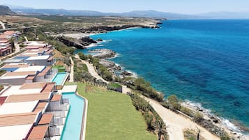 A coastal resort with multiple bungalow-style accommodations, a swimming pool, and a view of the ocean.