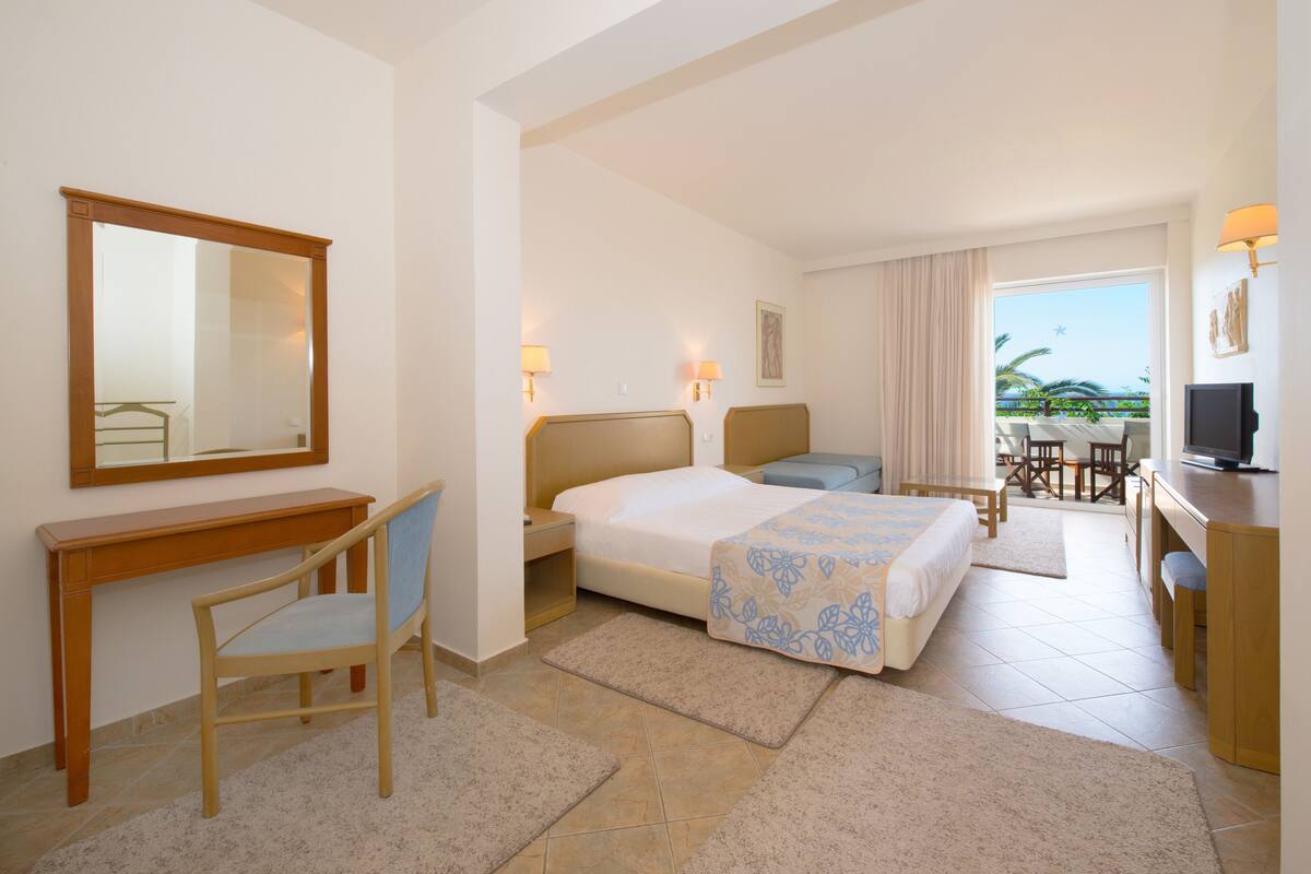 Une chambre d’hôtel équipée d’un lit, d’un bureau, d’une chaise, d’une télévision et offrant une vue sur l’extérieur.