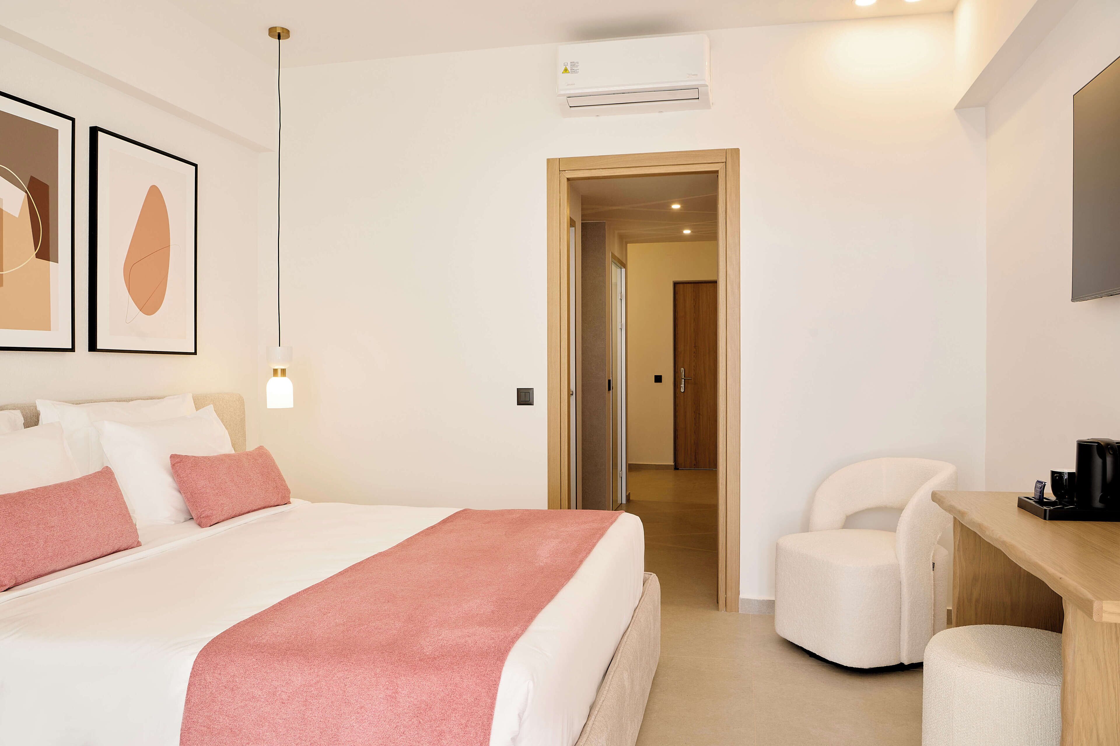 A hotel room with a bed, a desk, a chair, and a TV.