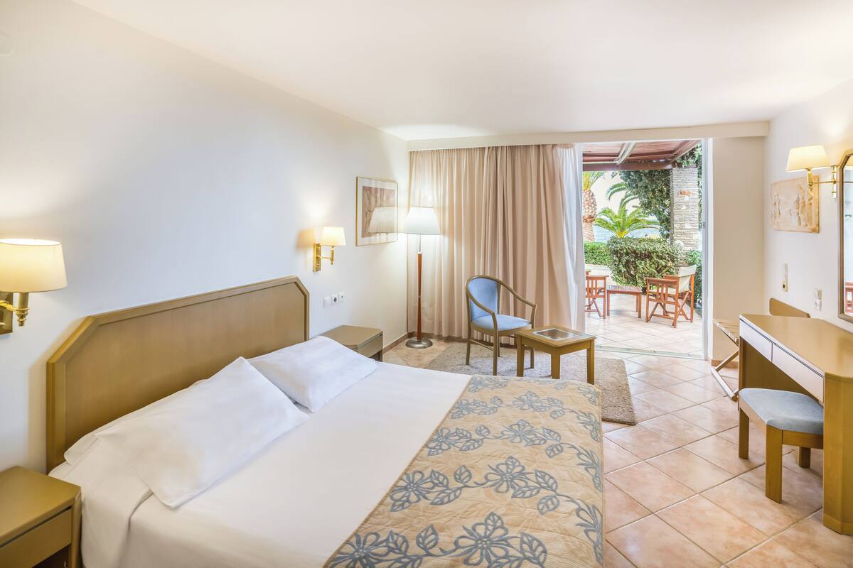 Une chambre d’hôtel équipée d’un lit, d’un bureau, d’une chaise et offrant une vue sur l’espace extérieur.