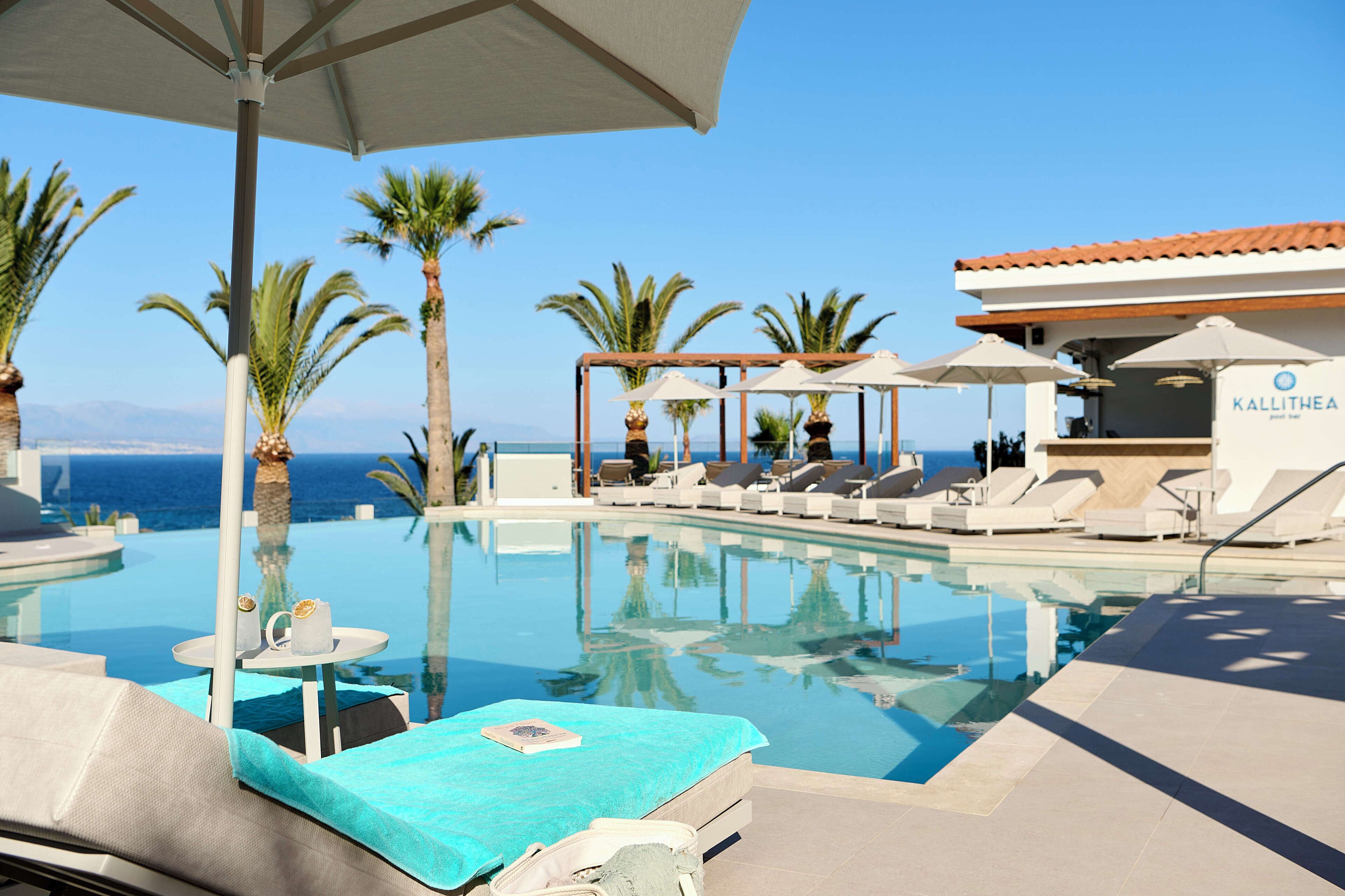 A poolside area with lounge chairs and umbrellas, a clear view of the ocean, and a building labeled 'Kallithea'.