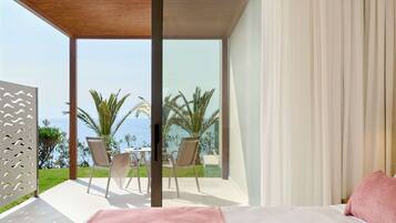 Un dormitorio con un ventanal grande, una cama con almohada rosa y vistas a palmeras y al mar.