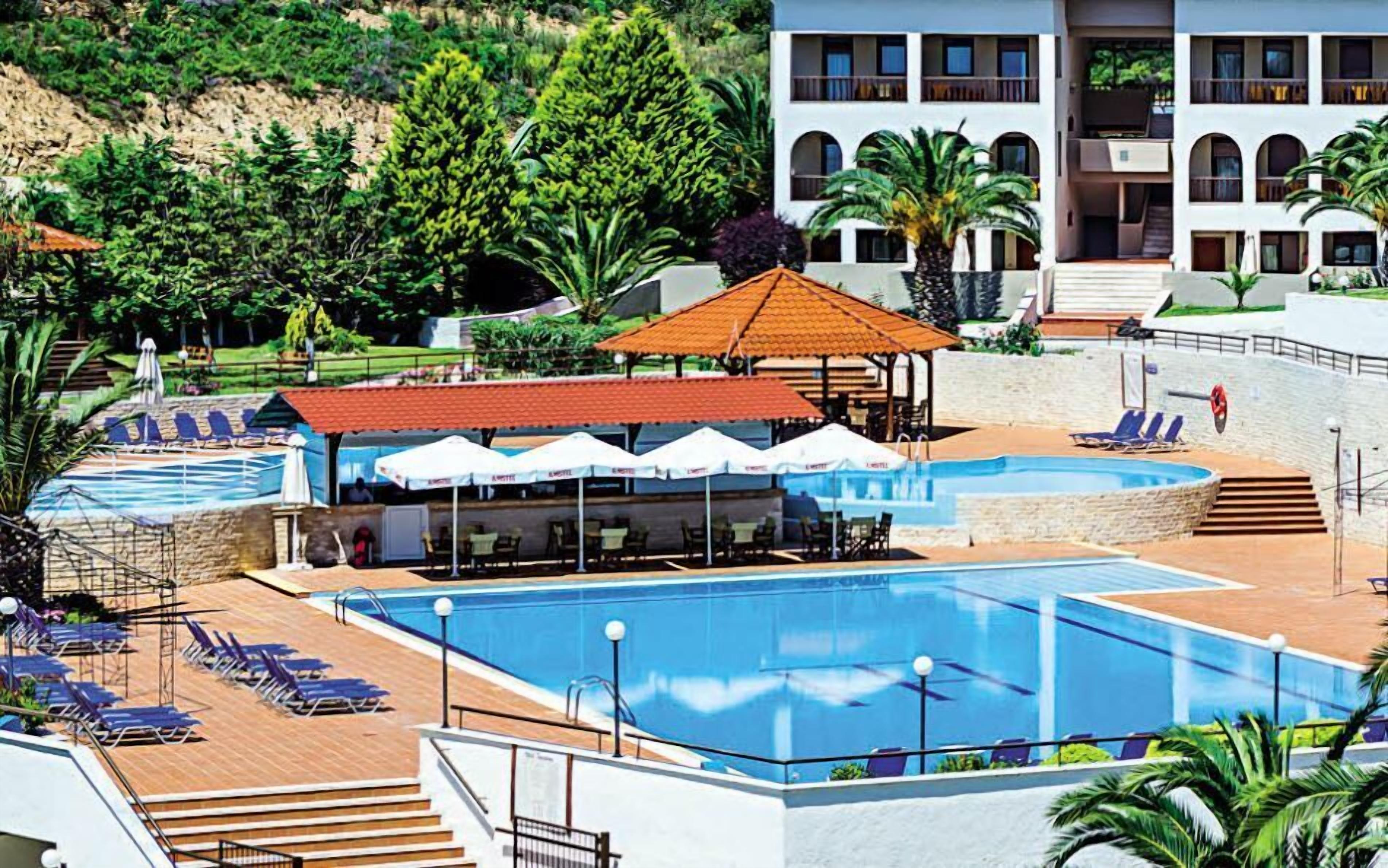 Et resort med flere swimmingpools, liggestole og et overdækket siddeområde.