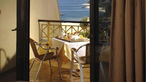 Ein Balkon mit einem Tisch für zwei Personen, mit Blick auf die Küste.