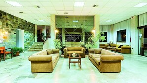 Eine geräumige Lobby mit hoher Decke, einer Steinwand und mehreren Sitzbereichen.
