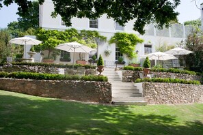 A white building with a stone staircase leading to a covered seating area with umbrellas. - The Haytor Hotel (Torquay)